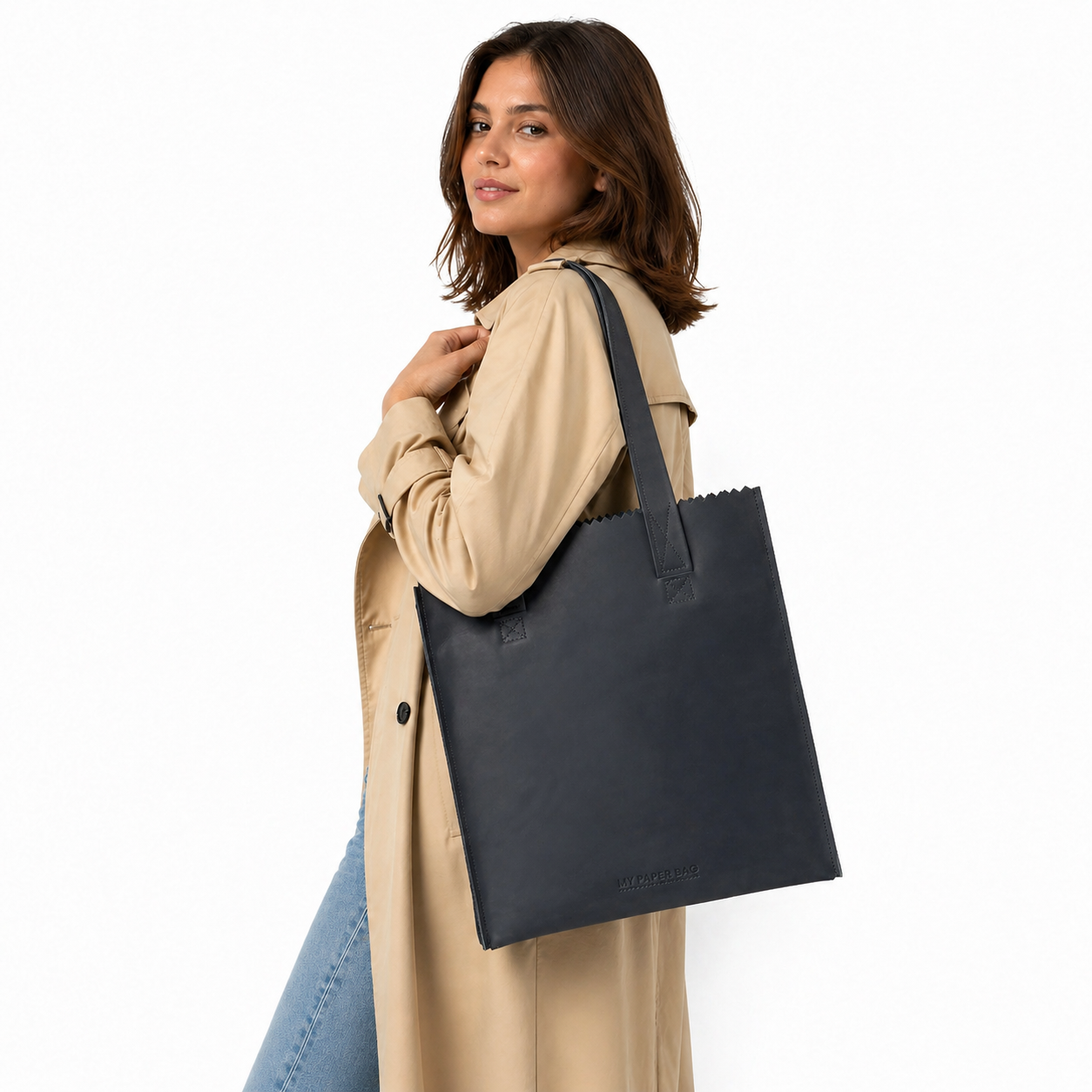 Woman holding a black tote bag against a white background