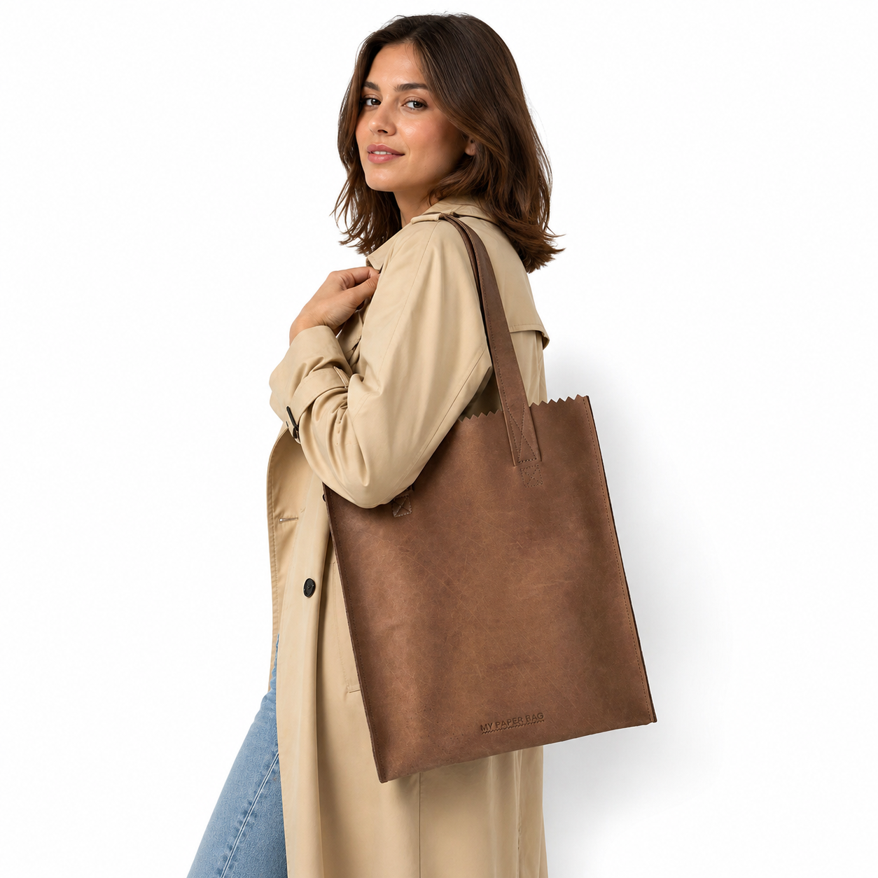 Woman holding a brown leather tote bag against a white background