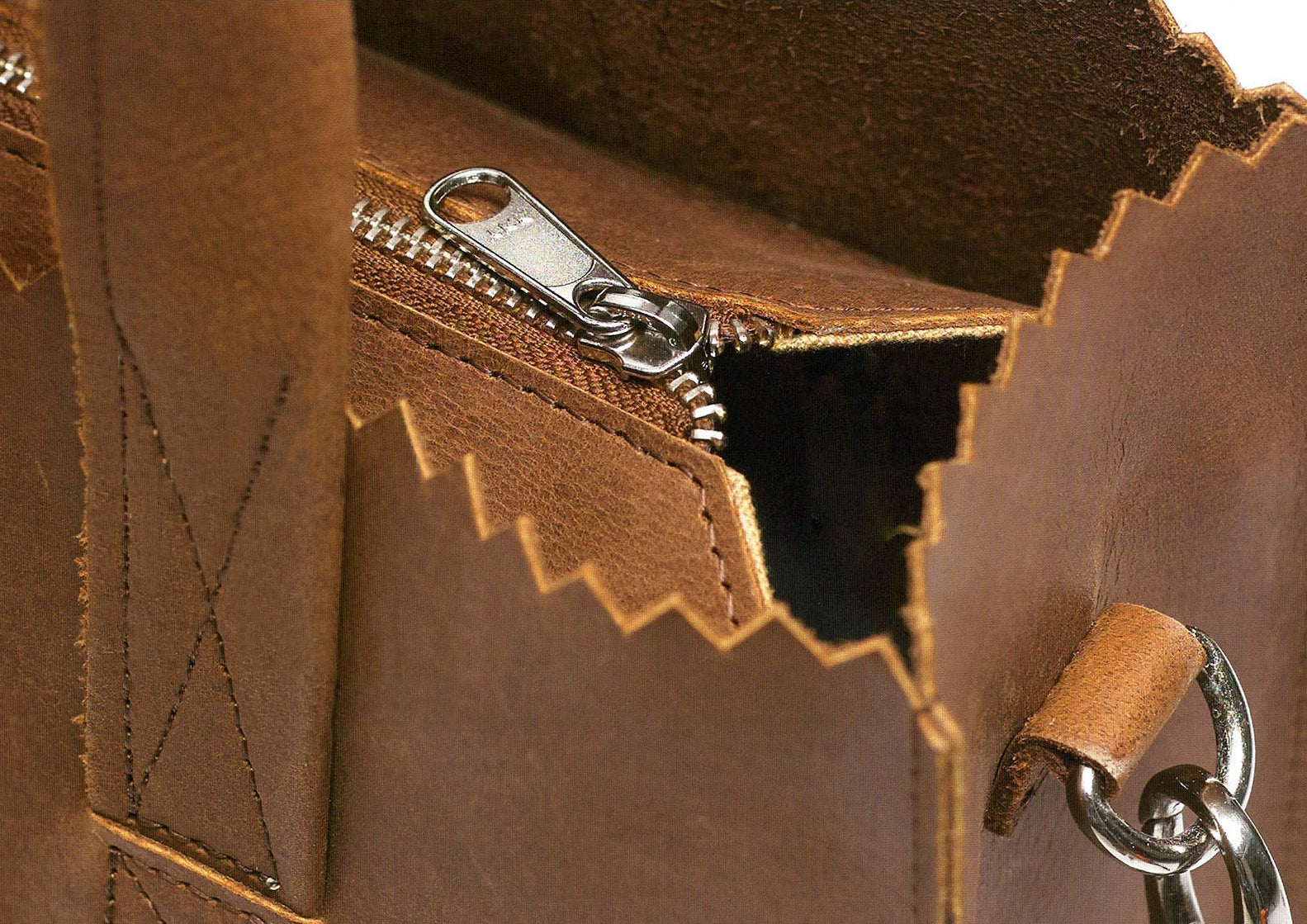 Close-up of a brown leather bag with a zipper and keychain.